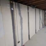 Interior view of a room with painted drywall, highlighting repairs from water intrusion and structural reinforcement with straps