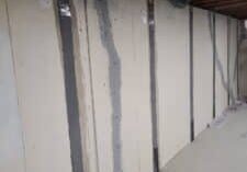 Interior view of a room with painted drywall, highlighting repairs from water intrusion and structural reinforcement with straps
