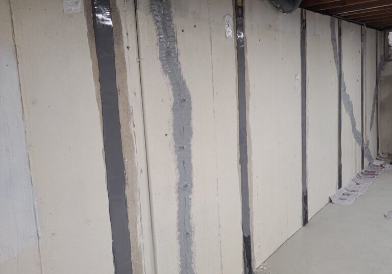 Interior view of a room with painted drywall, highlighting repairs from water intrusion and structural reinforcement with straps